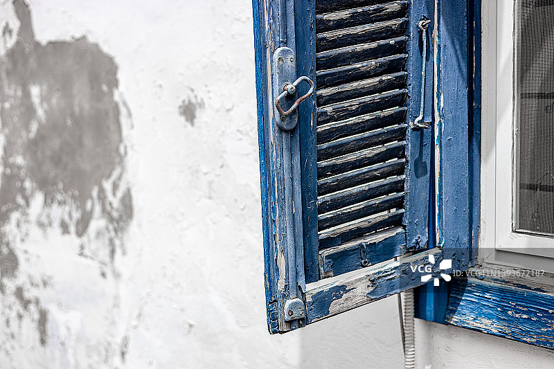 蓝色木质百叶窗特写，白色墙壁油漆剥落图片素材