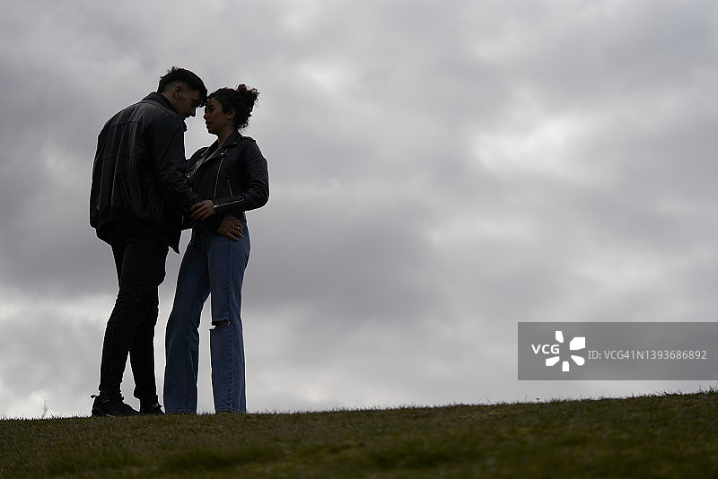 情侣在多云的秋日山丘上重逢，身着时尚图片素材