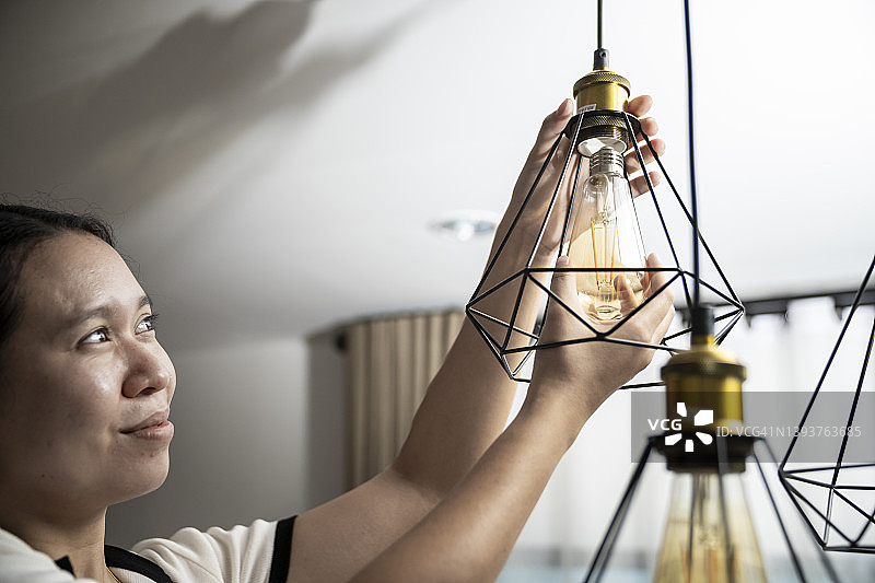 女人在家安装天花板照明设备图片素材