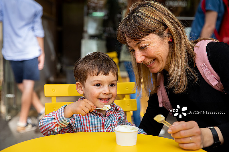 年轻母亲和儿子在冰淇淋店分享冰淇淋图片素材