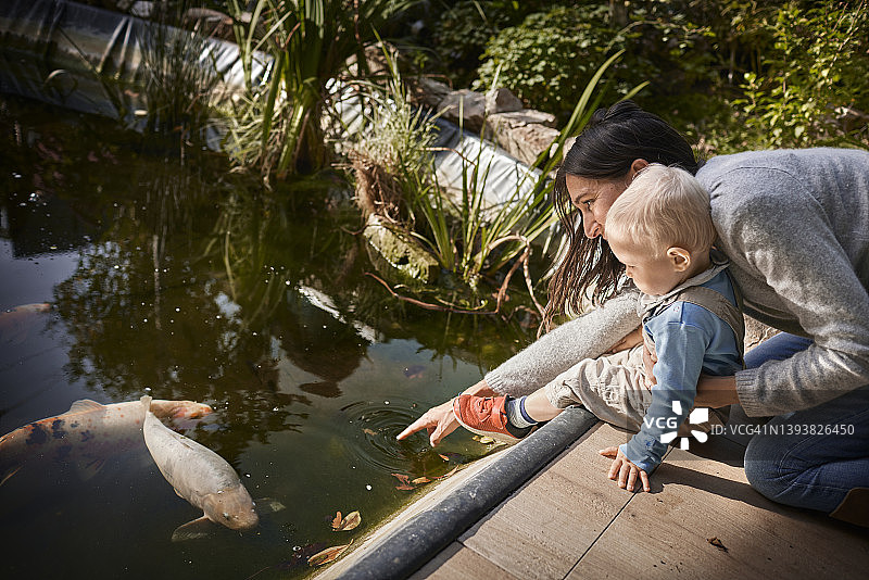母亲和宝宝儿子在花园池塘边图片素材