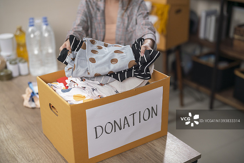 女人在房间里拿着装有捐赠盒的衣服，捐赠概念图片素材