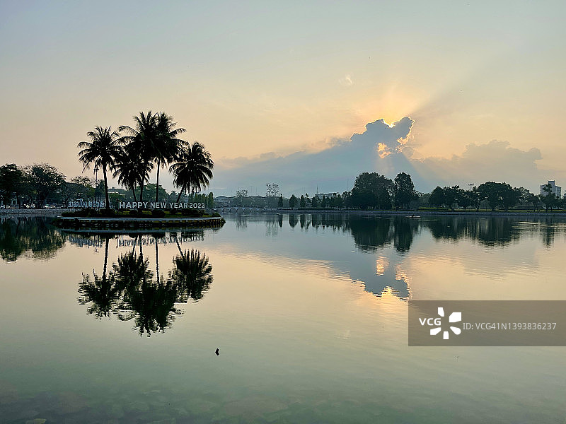 尖竹汶风光：椰子树在湖中小岛上倒映着美丽的日出天空，郑皇达信大帝公园图片素材
