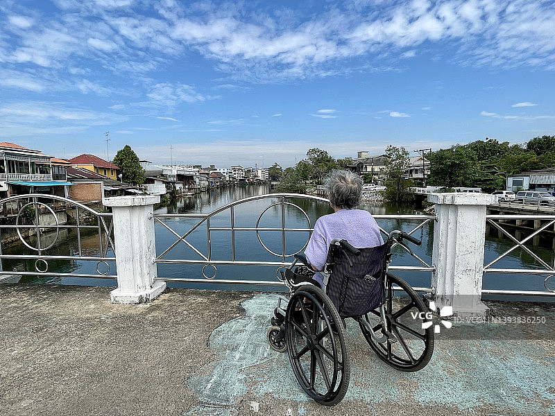 尖竹汶府风光(Chanthaboon Waterfront):坐在轮椅上的老妇人在桥上看尖竹汶河的景色图片素材