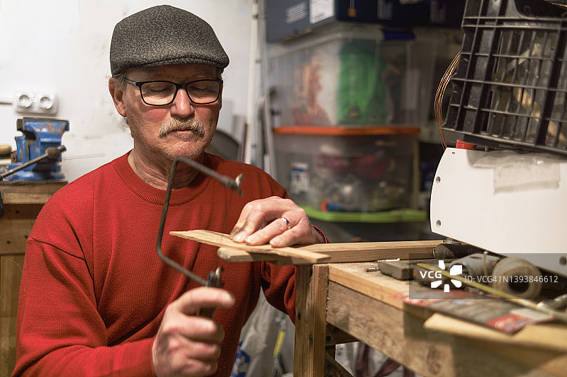 退休男人在工作室用弓锯木工，木工概念图片素材