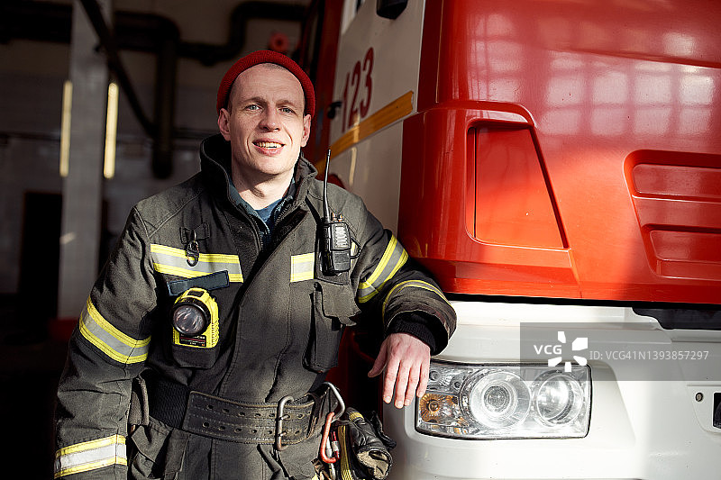 微笑的消防员倚靠在消防车上图片素材