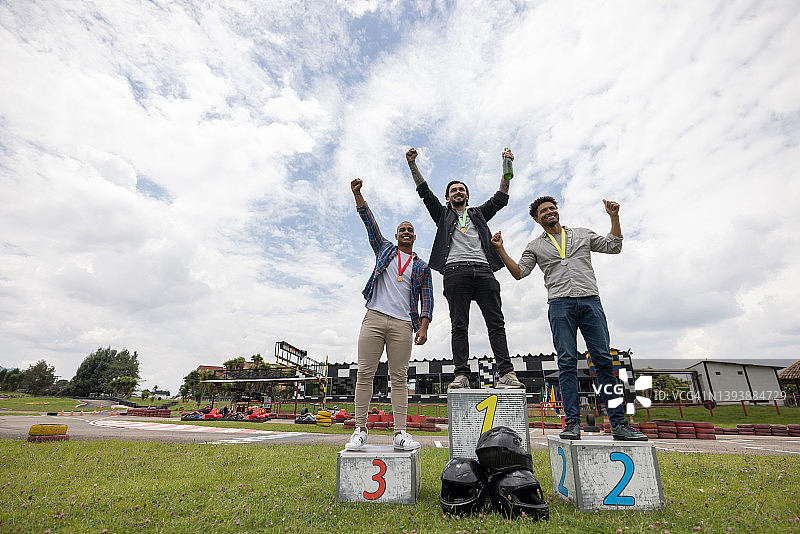 男人在卡丁车比赛后在领奖台上庆祝图片素材