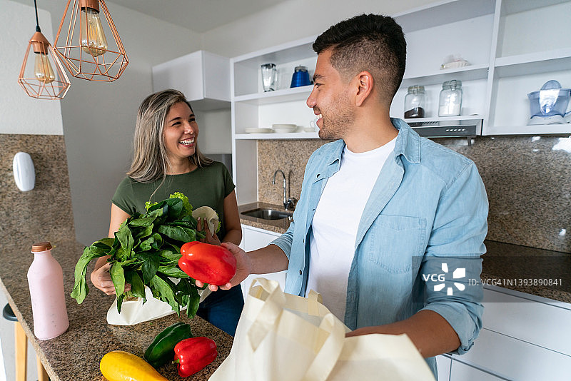 快乐的夫妇在家整理购物后的食品图片素材