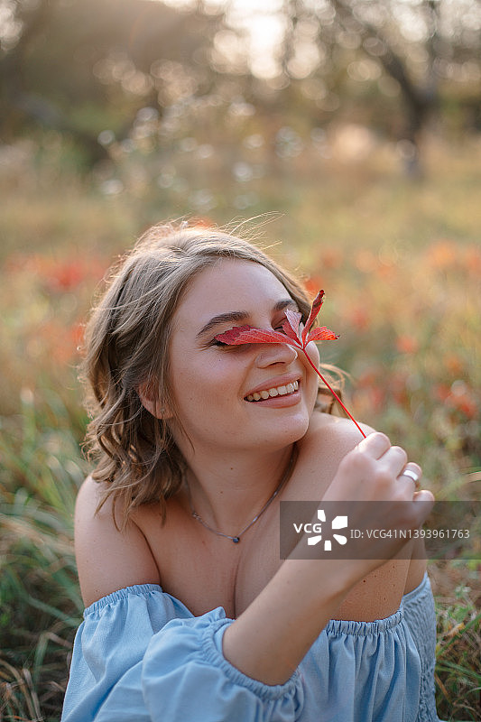 秋日，女子用红叶遮面特写图片素材