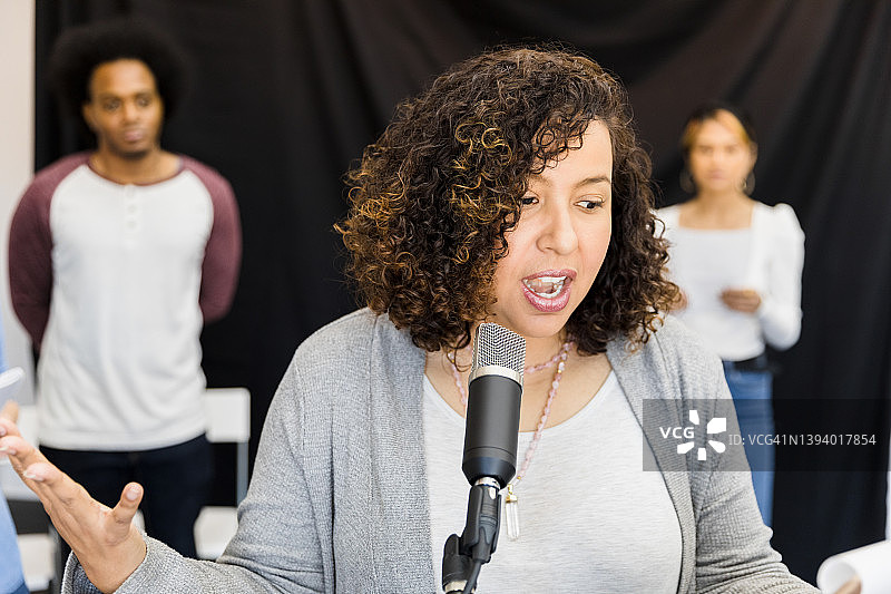 聚焦在麦克风前朗读的女人图片素材