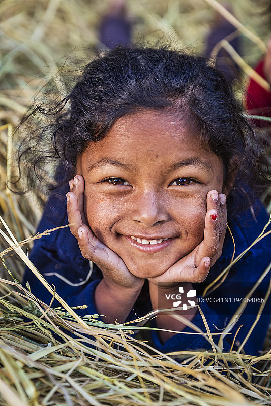 快乐的尼泊尔小女孩在安娜普尔纳山脉附近村庄的稻草地里玩耍图片素材