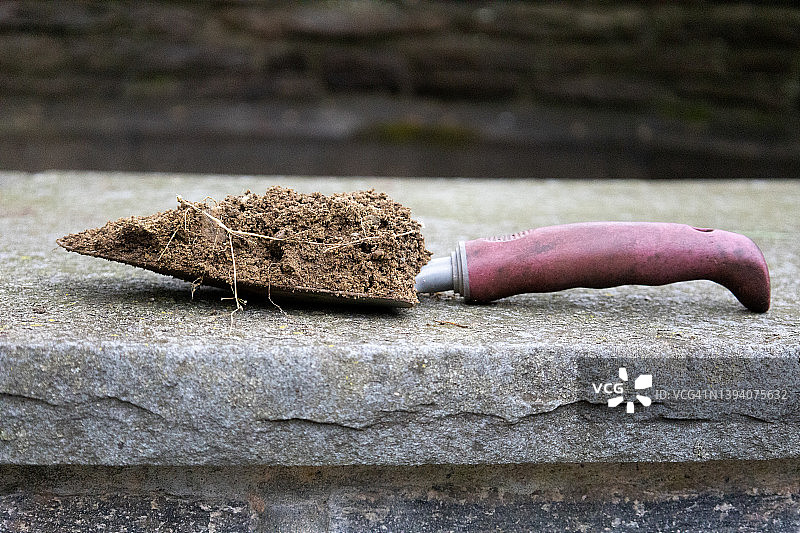 泥铲和石板表面的土堆图片素材