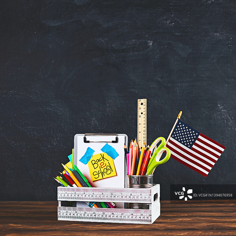 装满返校用品和美国国旗的木箱，带有文字空间的黑板背景图片素材