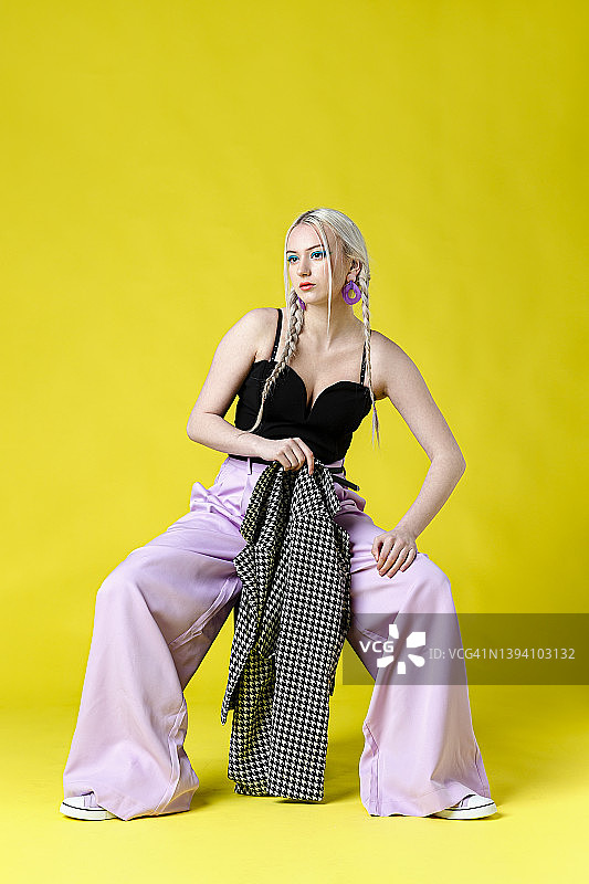 穿着时尚的女人在纯色背景前图片素材