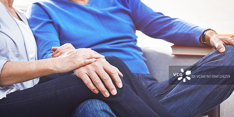 充满爱意的成熟夫妇在家中沙发上放松时手牵着手特写图片素材