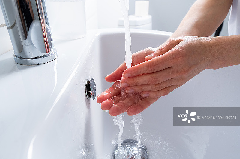 一名妇女在浴室、家中或公共场所用肥皂洗手消毒，预防疾病，讲究卫生。卫生概念，使用非接触式给皂机，遵守疫情和冠状病毒措施。图片素材