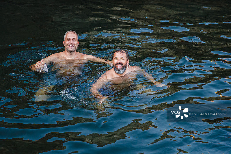 两名男子在海中游泳放松，面带微笑地看着镜头图片素材