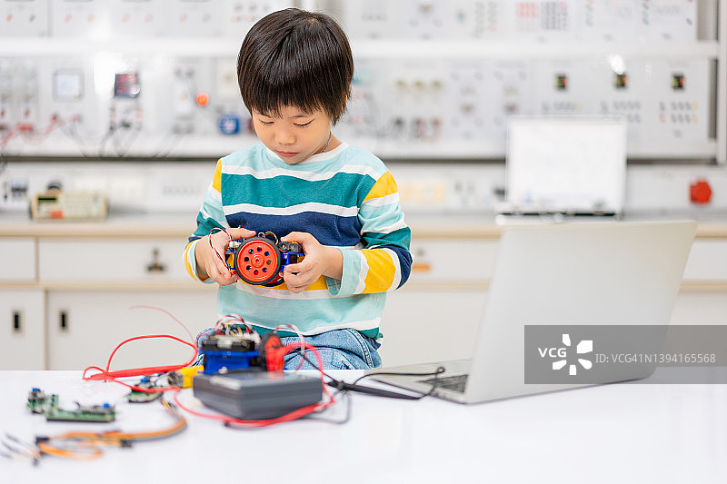 亚洲儿童在STEM课堂上用电子板编码和组装机器人汽车图片素材