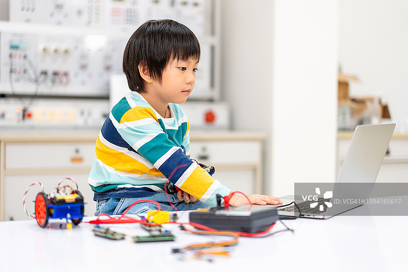 亚洲儿童在STEM课堂上用电子板编码和组装机器人汽车图片素材