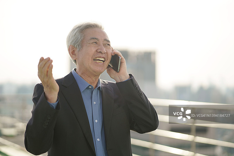 中年男子愉快地用智能手机交谈图片素材