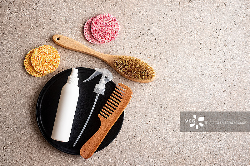 混凝土背景上的环保面部、头发和身体护理必需品套装（木制身体刷、清洁手套、清洁海绵、发刷、喷雾、保湿霜）。家庭水疗，平铺。零浪费理念。图片素材