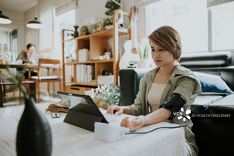 用于测量血压的医疗设备，女性在家隔离期间与医生交谈，远程医疗图片素材