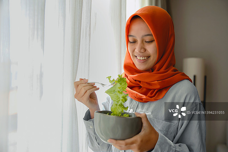 在家吃绿色沙拉的穆斯林妇女图片素材