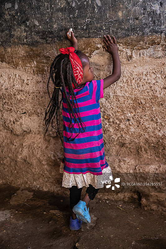 非洲肯尼亚孤儿院，小女孩在黑板上写字图片素材