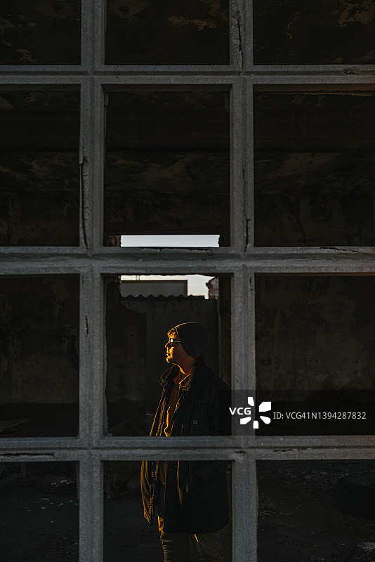 男孩在废弃建筑的窗后凝视阳光图片素材