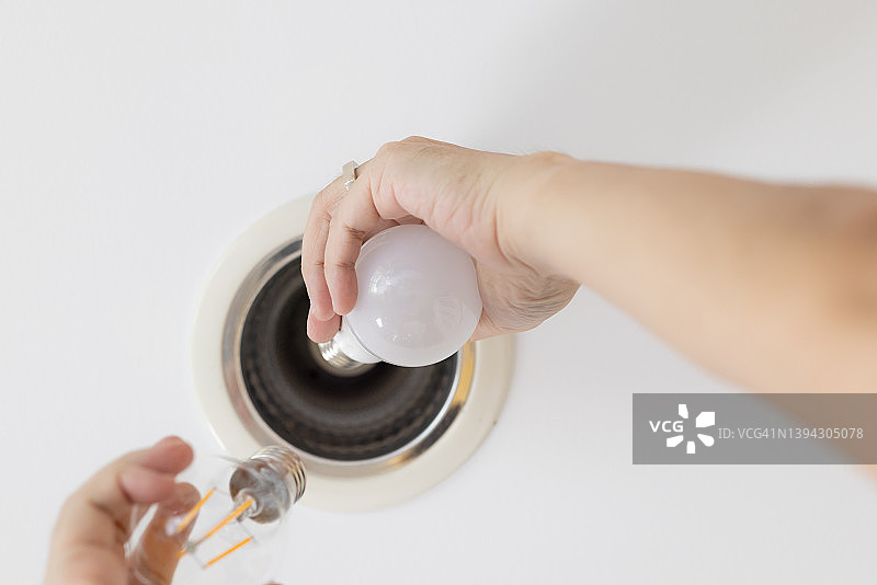 手部近景：更换LED灯泡，家居改善与绿色住宅概念图片素材