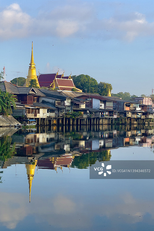尖竹汶府风光：尖竹汶海滨，泰国寺庙的金色宝塔和河边的木屋在晴朗的蓝天下倒映着图片素材