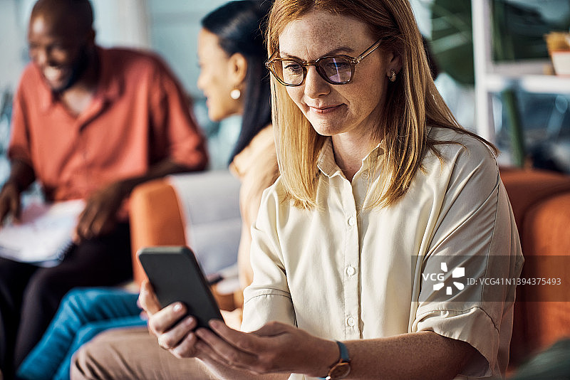 工作中浏览手机的年长的白人女商人图片素材