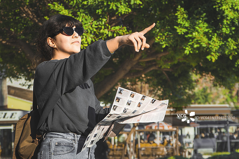 年轻女子背着背包，拿着地图探索古城或旧集市图片素材