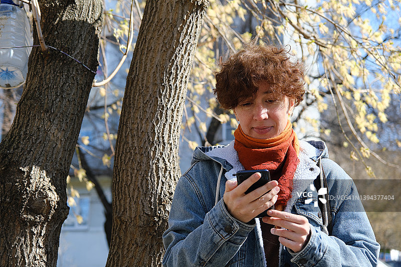 女人在阳光明媚的街道上使用手机图片素材