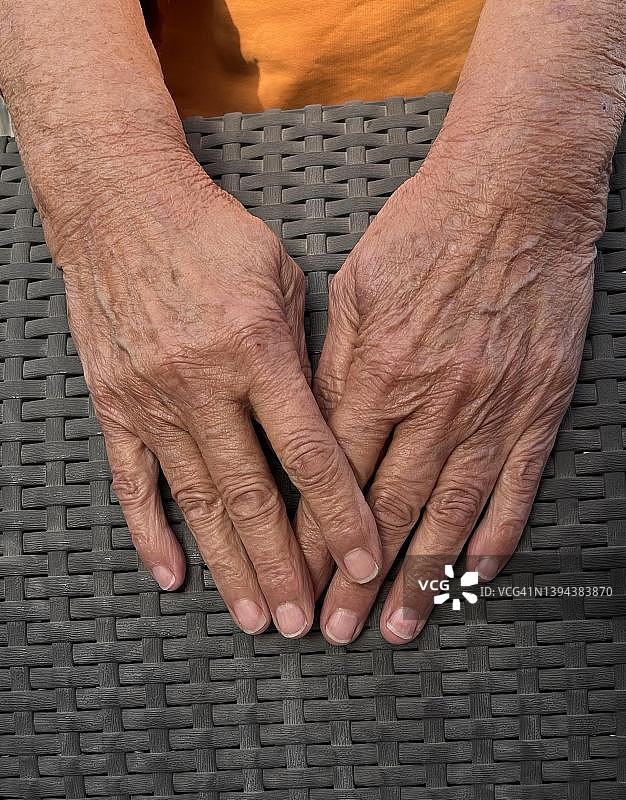 一位老妇人在柳条椅的柳条上的皱纹双手，德国图片素材