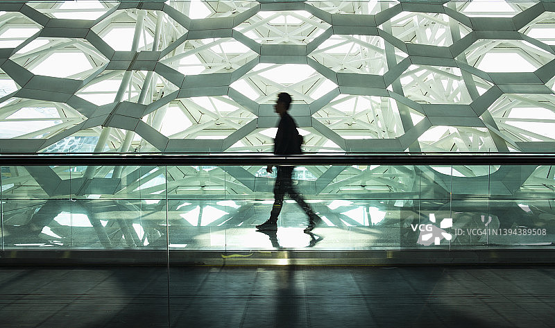 男人独自走在现代走廊里图片素材