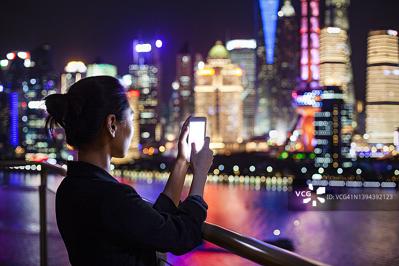 年轻女子在上海市中心用手机拍照图片素材