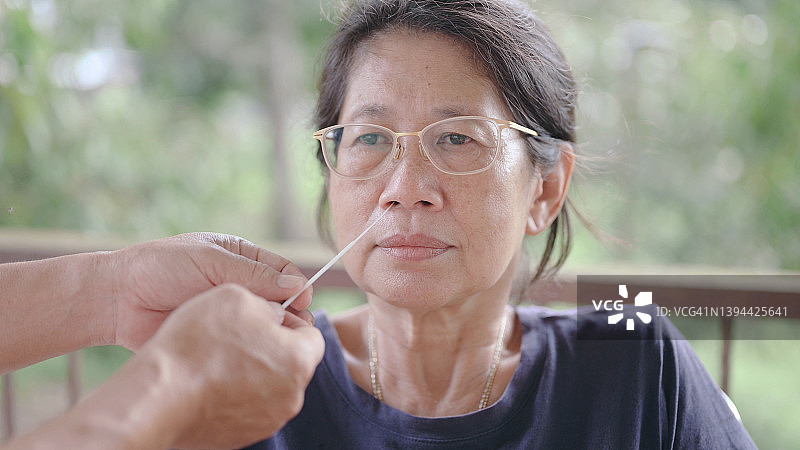 亚洲妇女在医疗诊所进行新冠病毒咽喉和鼻拭子检测图片素材