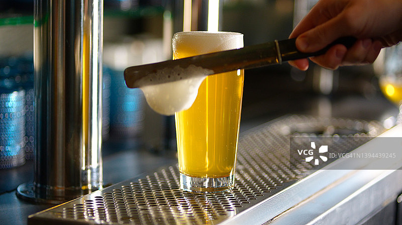 一杯正在刮去泡沫的啤酒图片素材