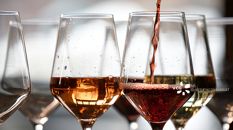 各种葡萄酒杯，一个红酒杯正在被倒满图片素材