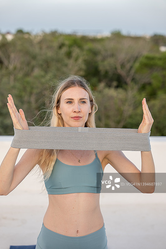 年轻女子在屋顶健身，使用阻力带图片素材
