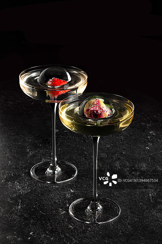 用冰中鲜花装饰的透明鸡尾酒玻璃高脚杯图片素材