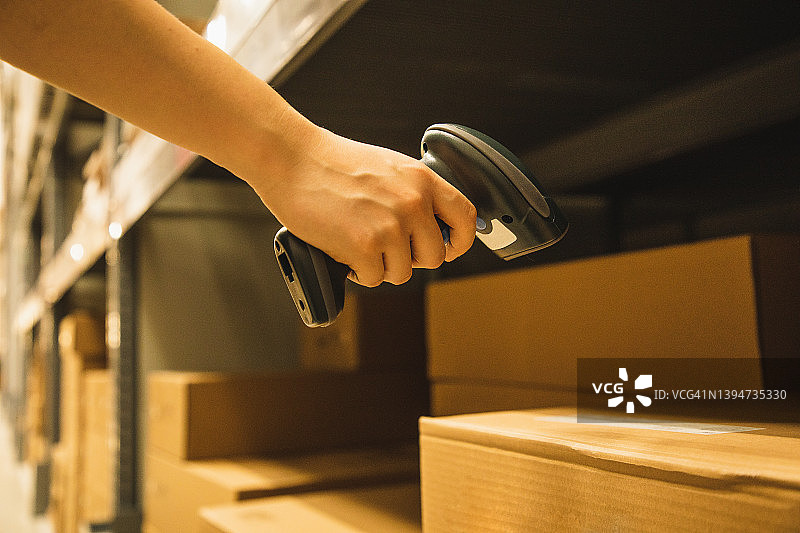 亚洲女人在仓库工作时手持条形码扫描仪的特写图片素材