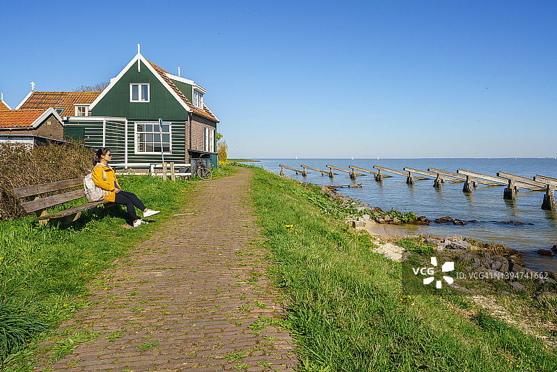 荷兰马肯渔村，坐在海边长椅上的女游客图片素材
