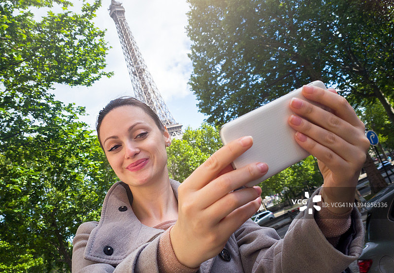 用智能手机拍摄埃菲尔铁塔的女人图片素材
