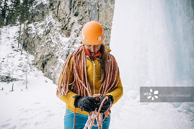 在加拿大落基山脉寒冷的一天，女子攀冰时卷起绳索图片素材