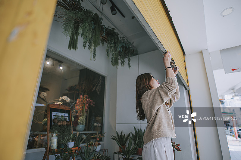 中国女花店主推开金属栅栏门开始营业图片素材