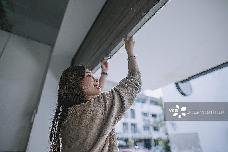 中国女花店主推开金属栅栏门开始营业图片素材