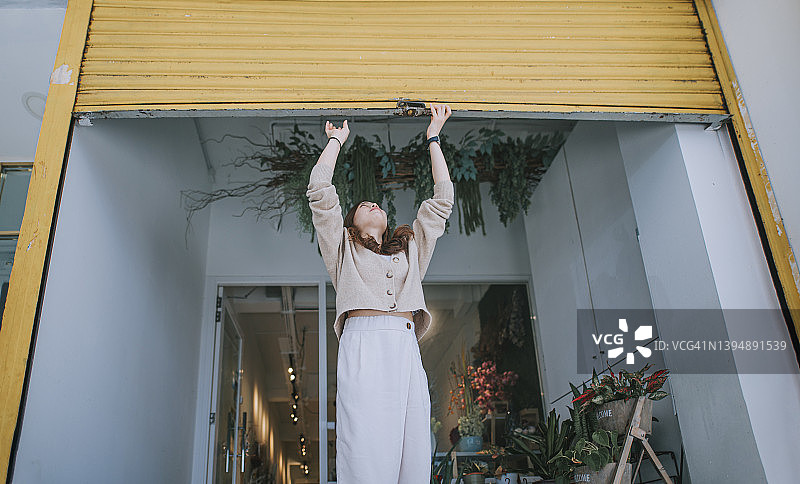 中国女花店主推开金属栅栏门开始营业图片素材