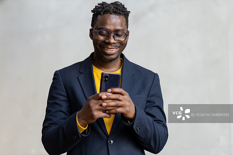 微笑的年轻黑人男商人正在使用智能手机图片素材